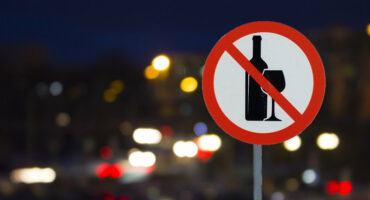 the Sign the prohibition of alcohol and the night road with cars